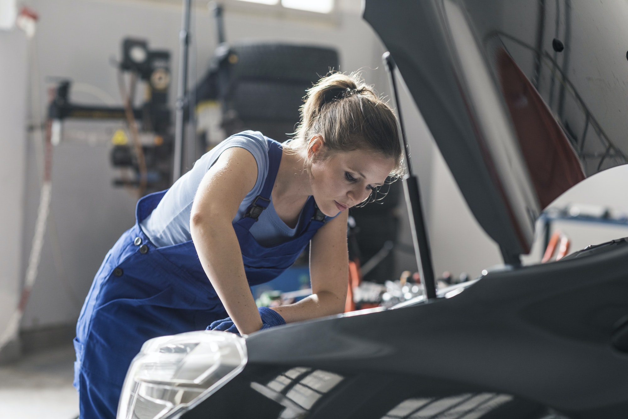 Professional female mechanic repairing a car