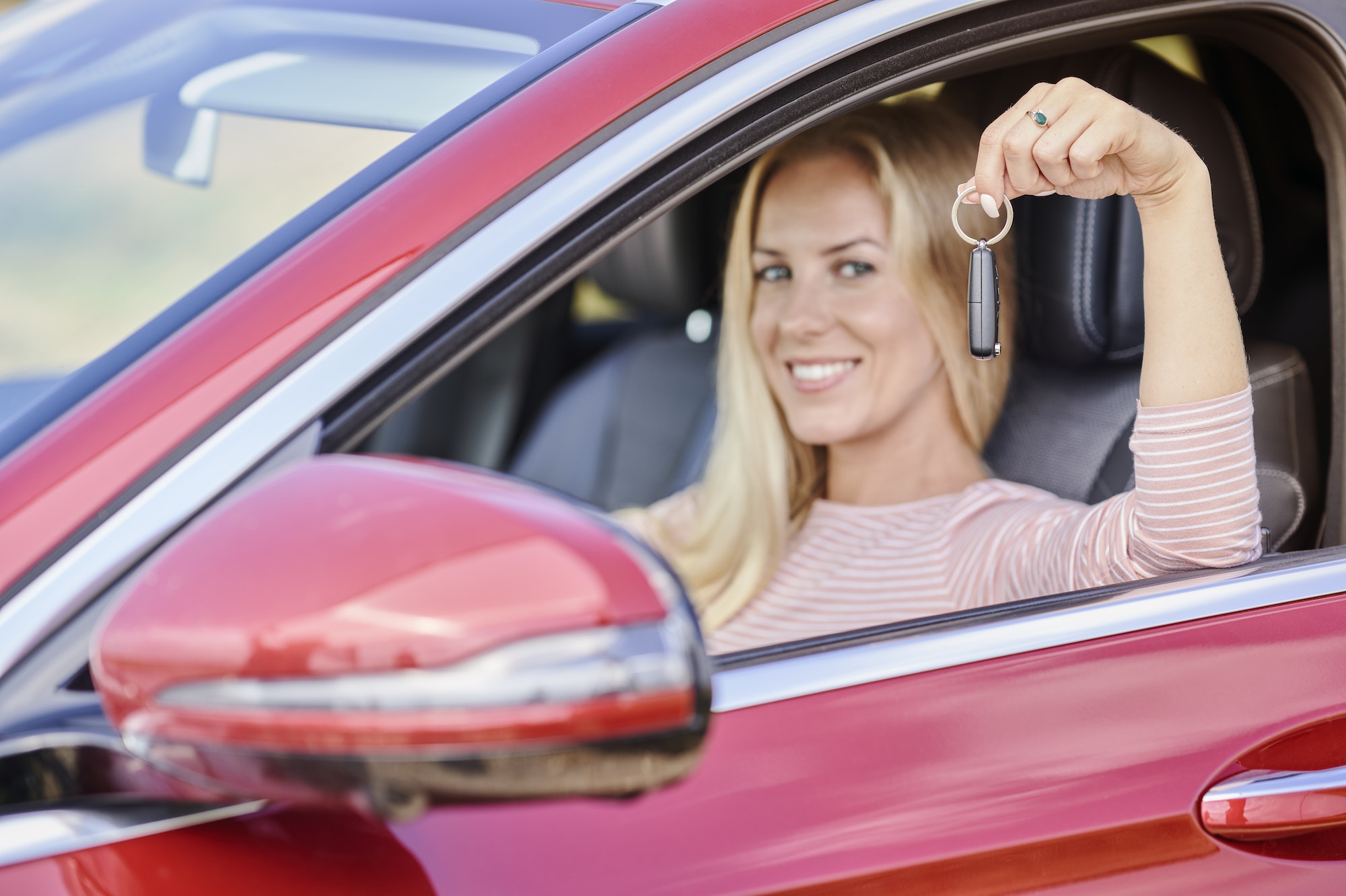 Smiling woman in the car with the keys